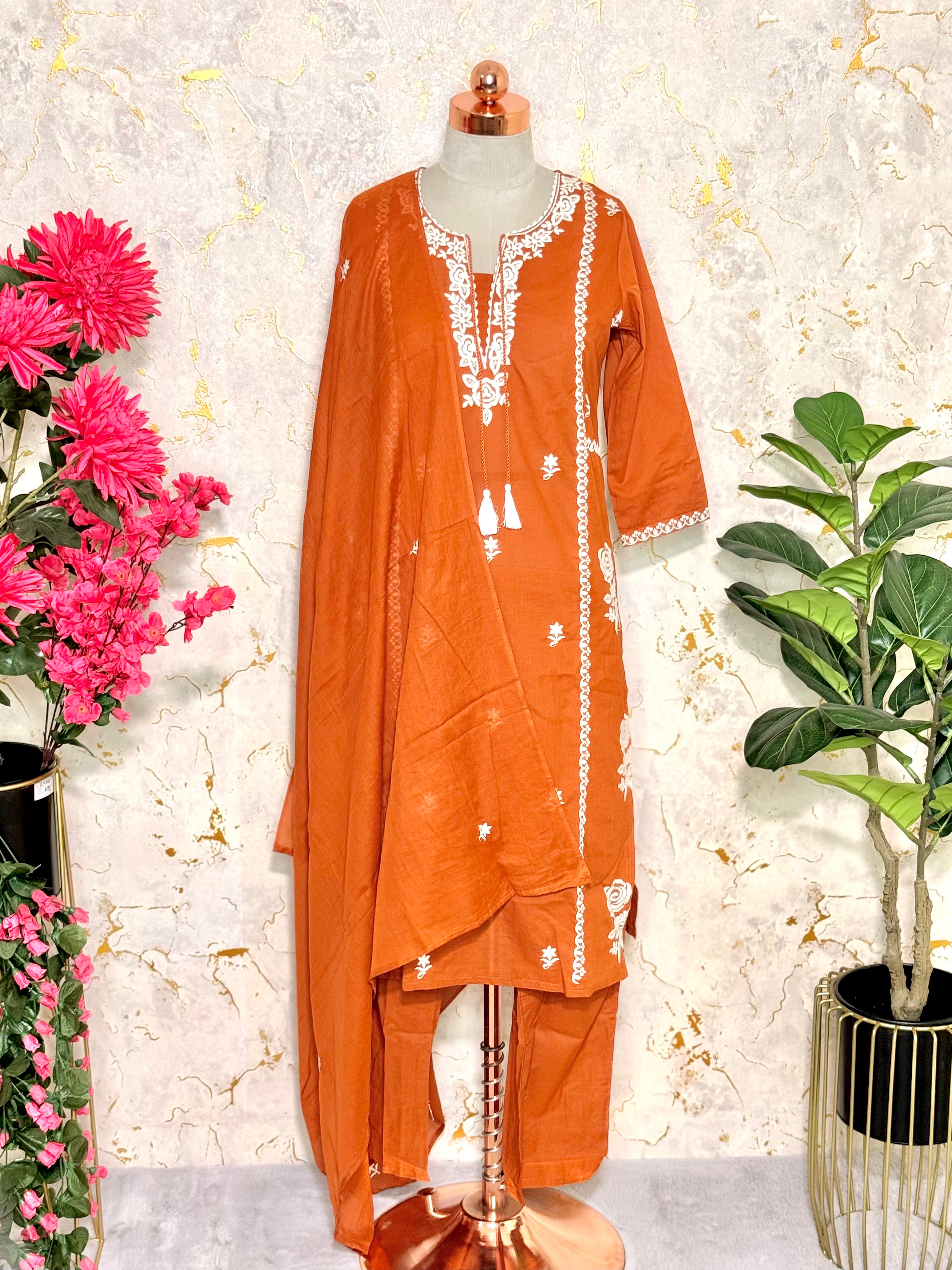 Rust traditional outfit with white embroidery on dress.